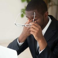 Man rubbing eyes while looking at computer